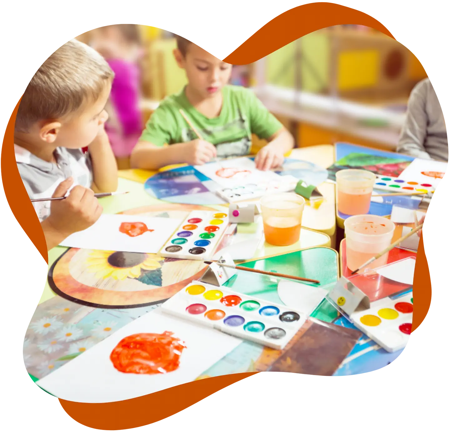 Kinder malen gemeinsam mit Wasserfarben an einem Tisch