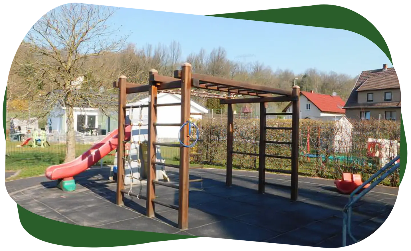 Spielplatz des Kindergarten Sonnenschein mit Klettergerüst, Rutsche und Schaukel